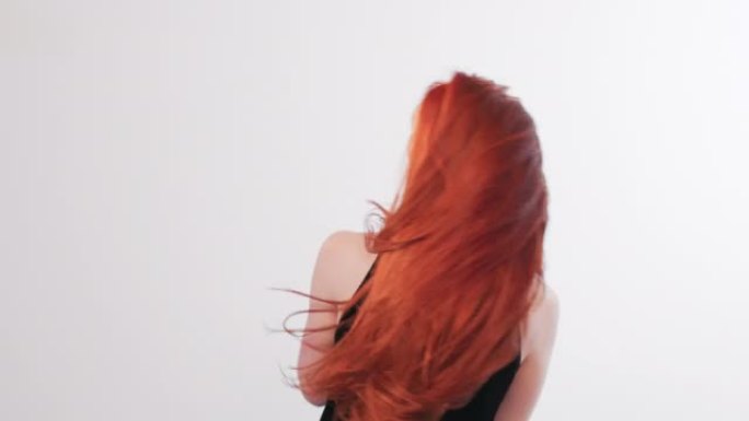 美丽诱人的红发女人扔长发。对着镜头微笑，躲在头发后面