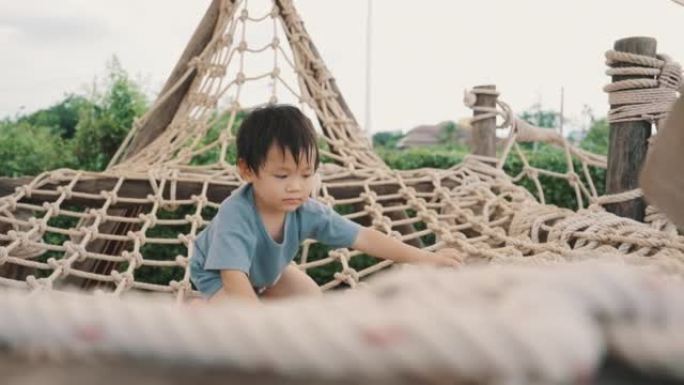 亚洲男孩在操场上爬绳子