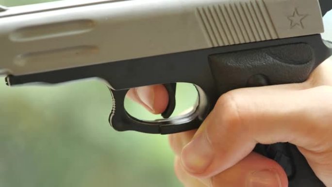 一个男人用颤抖的手慢慢地扣动廉价玩具枪的扳机，物体细节，特写。射击武器，紧张射手，枪支安全法律规则，