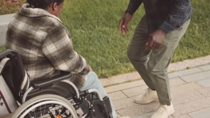 男子帮助残疾妇女从轮椅上站起来