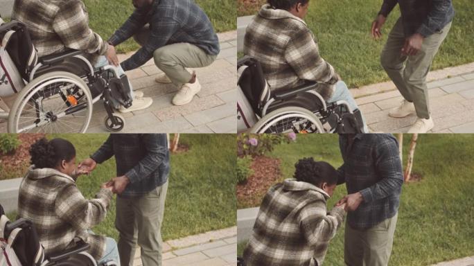 男子帮助残疾妇女从轮椅上站起来