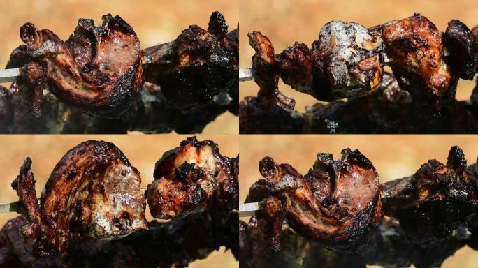 关闭缓慢旋转的串串，大块的羊肉在木炭烤架上煮熟时冒泡，吸烟和滴落
