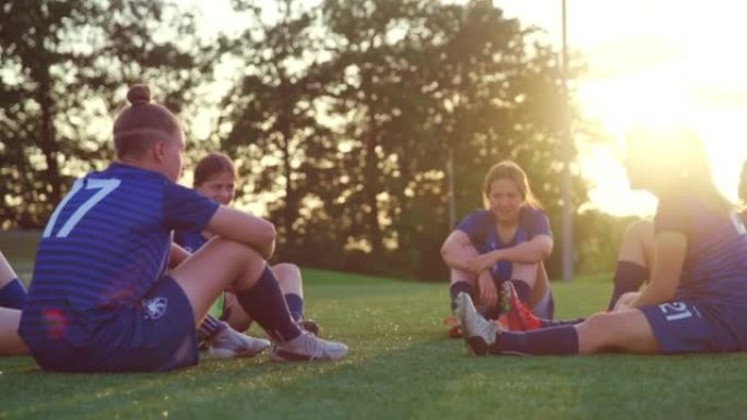 足球队的年轻女性坐在运动场上聊天