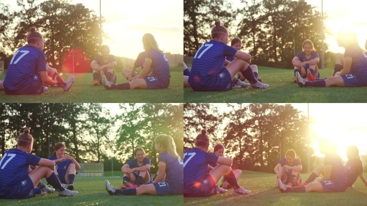 足球队的年轻女性坐在运动场上聊天