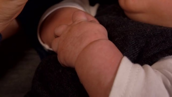 婴儿奶瓶的可爱小手在母亲的怀抱中喂养的超级特写镜头