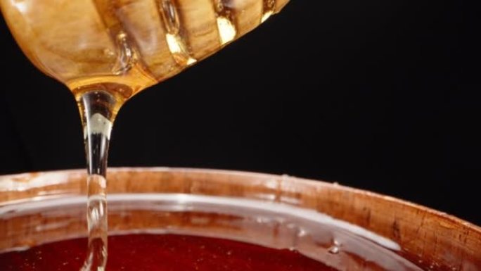 一盘木头蜂蜜。蜂蜜从木勺中排出，超级宏观。慢动作。