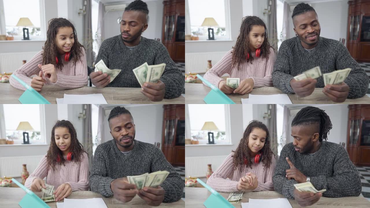 非裔美国富人数钱与坐在客厅桌子旁的少女分享钱的前视图肖像。有钱的单身父亲和十几岁的女儿在家中现金的肖