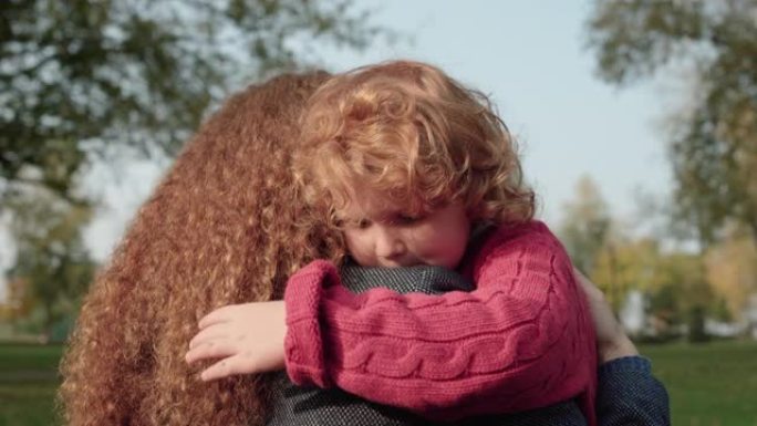 红发孩子拥抱母亲，舒适和保护的感觉，家庭之爱