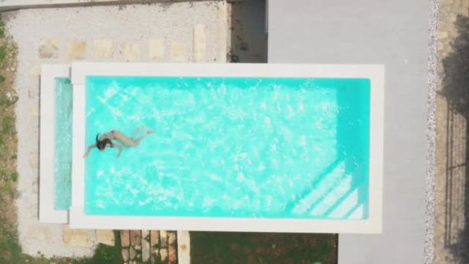 空中无人机拍摄了一名女子在游泳池里游泳的腿