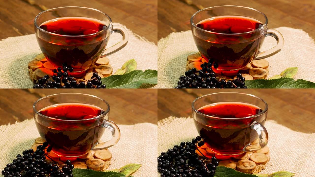 转盘上的玻璃杯中的天然红莓茶。黑接骨木浆果中的浆果茶。顺势疗法果汁