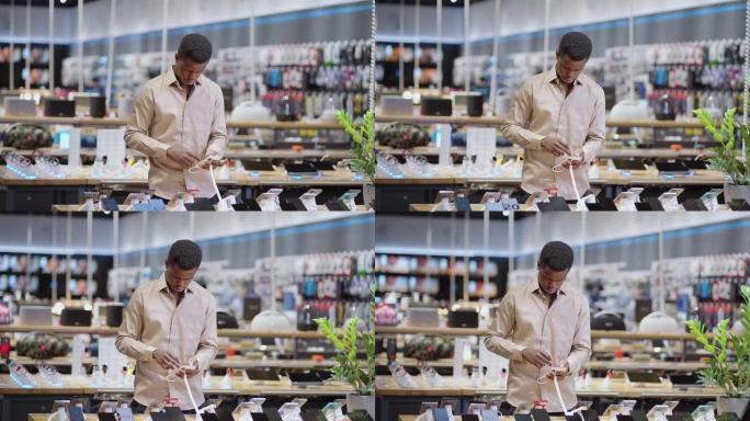 美国黑人男子正在数字设备商店中选择智能手机，在交易大厅中选择男性购物者的肖像