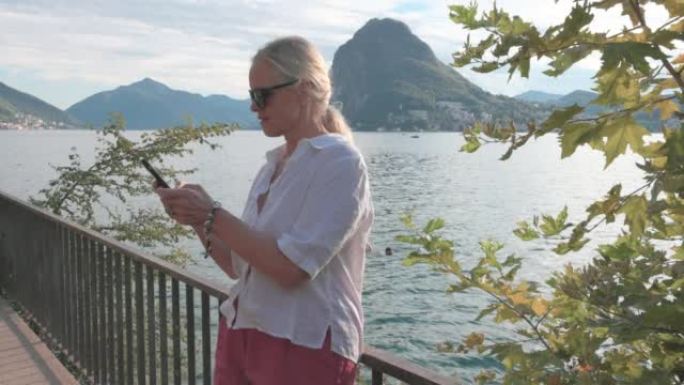 女子站在湖边玩手机