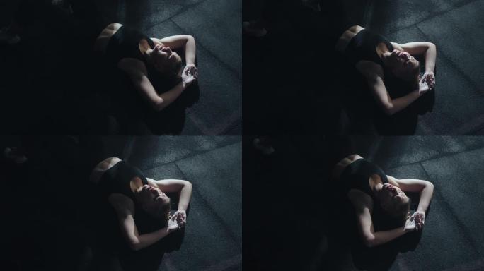 精疲力竭的女运动员躺在健身房的地板上，剧烈运动后呼吸困难