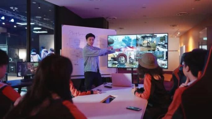 亚洲中国电竞团队教练在带有白板和电视的会议室举行的大型电子游戏比赛前向团队分析简报策略