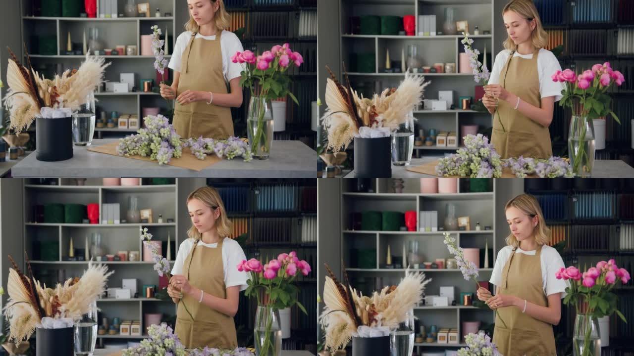 职业女性花店在花店工作时切一朵花创造美丽的花束。在花店工作室工作的花卉艺术家。手工花艺