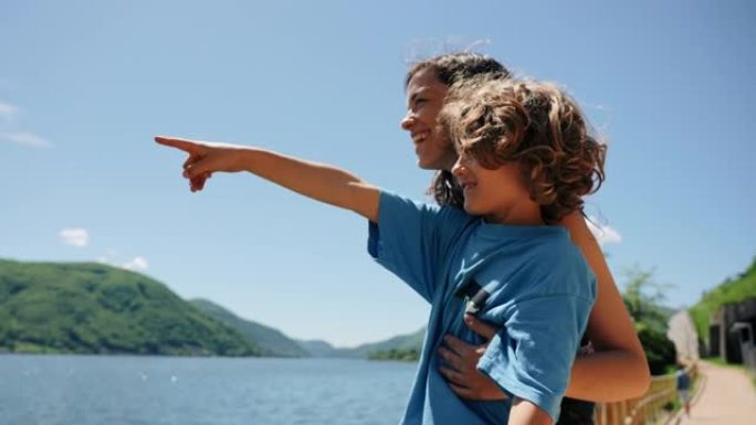 母亲和小男孩一起看着湖泊和山脉的景色，为生活感到兴奋