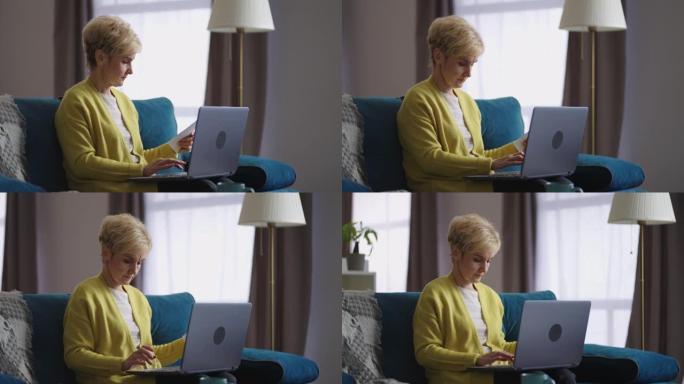 老年妇女正在网上工作，在家中通过互联网在现代笔记本电脑的键盘上打字，在室内进行肖像