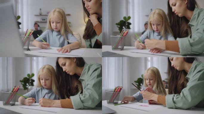 漂亮的母亲帮助女儿坐在家里的桌子旁做作业。女儿在家和妈妈一起上在线课。用电脑远程学习的孩子。