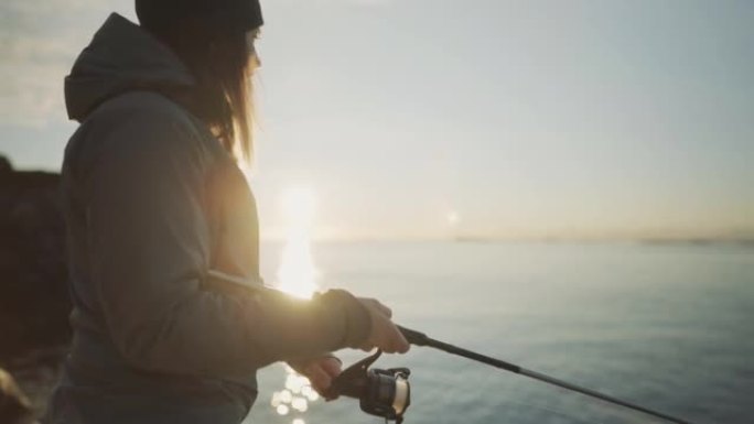 女人用钓竿在海里钓鱼，抓鳕鱼