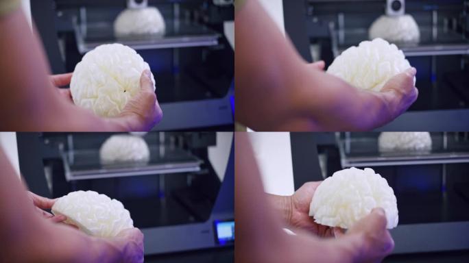 男性手握并检查3D大脑模型，而3D打印机正在构建另一个