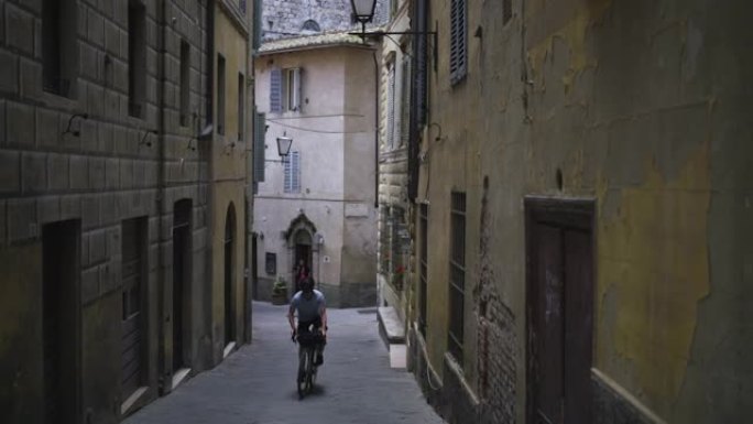 自行车包装工骑上中世纪的城镇街道