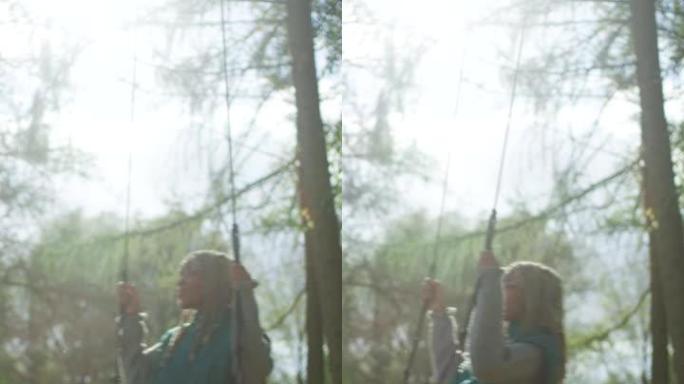 非洲民族少女在秋季公园的秋千上来回摇摆。垂直视频