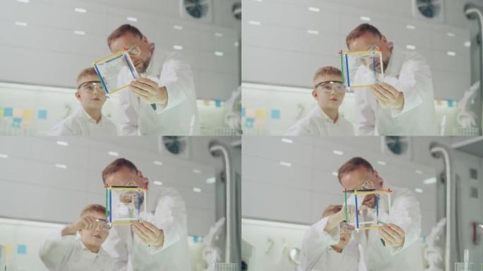和他的老师一起进行科学实验的男孩。在实验室玩得开心。用肥皂泡液体研究表面张力