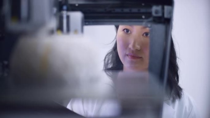 LD亚洲女生物医学工程师在3D打印机中俯瞰大脑模型的构建