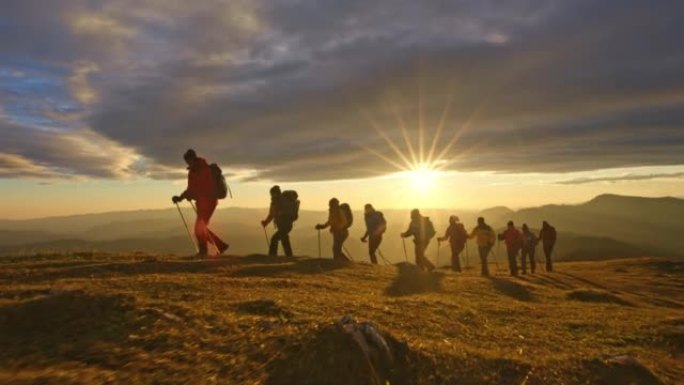 空中SLO MO远足团体在日落时在山顶行走