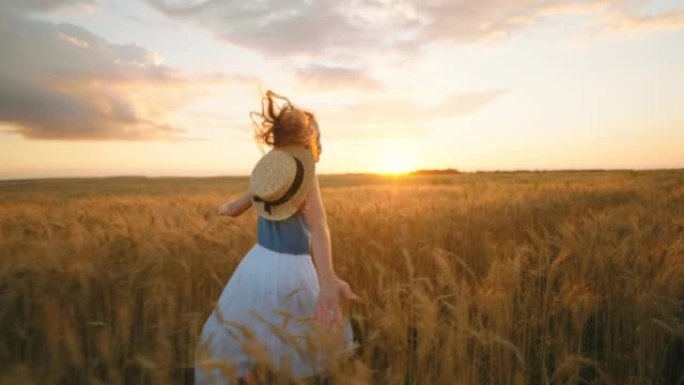 迷人的小女孩在风景如画的日落时间在金色的黑麦球场上奔跑，慢动作拍摄