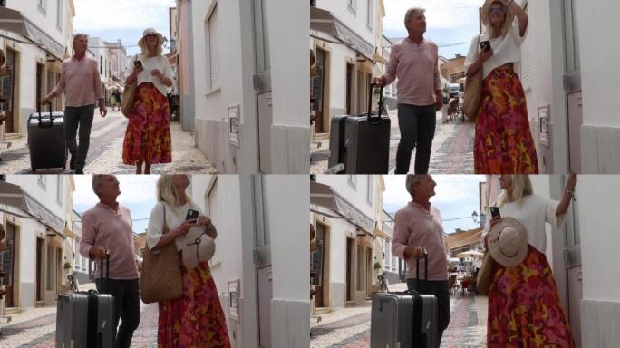 旅行夫妇沿着五颜六色的城市走廊拉手提箱