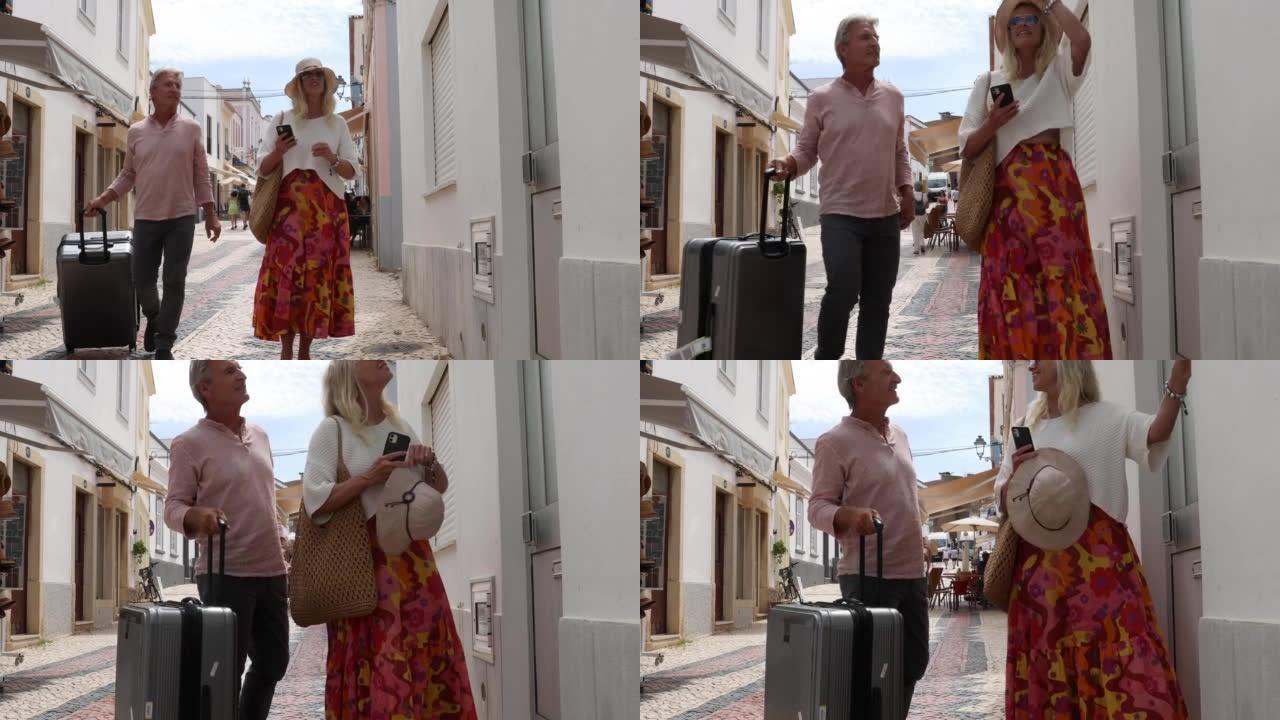 旅行夫妇沿着五颜六色的城市走廊拉手提箱