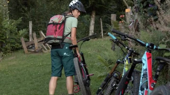一名年轻的女山地车手停下并放下自行车与其他自行车的细节拍摄