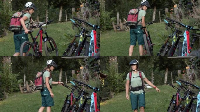 一名年轻的女山地车手停下并放下自行车与其他自行车的细节拍摄