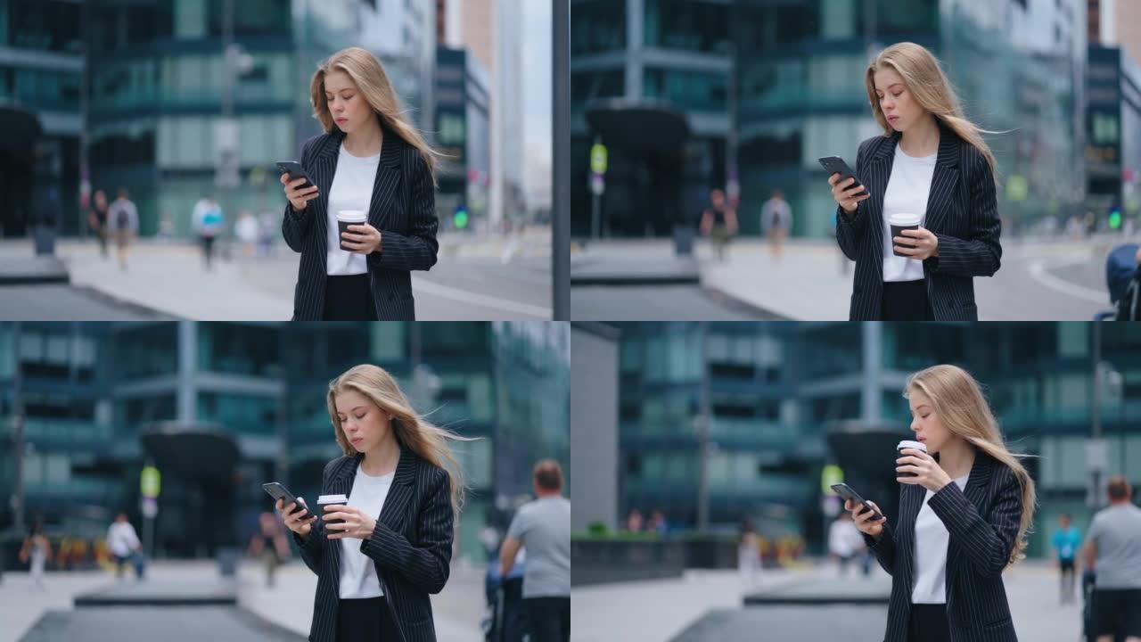 美丽的金发女郎正站在城市的街道上，用智能手机看新闻