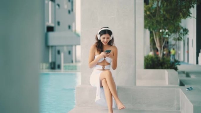 自信的女人一边听音乐，一边呆在游泳池里。
