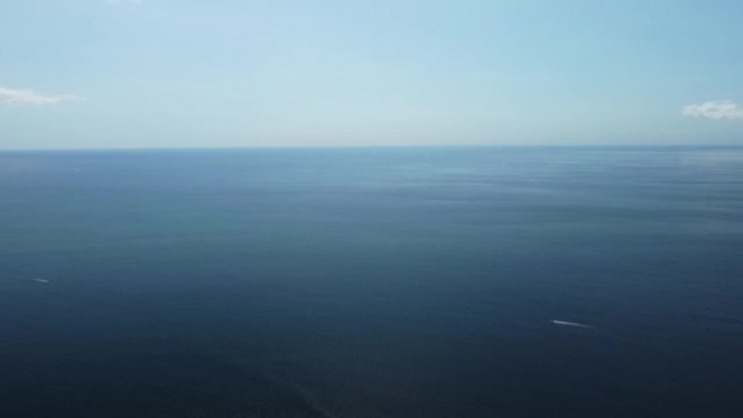 从上方俯瞰平静的蔚蓝海和火山岩石海岸。运动中水面上的小波模糊。自然夏季海洋海滩背景。没人。假期、假期