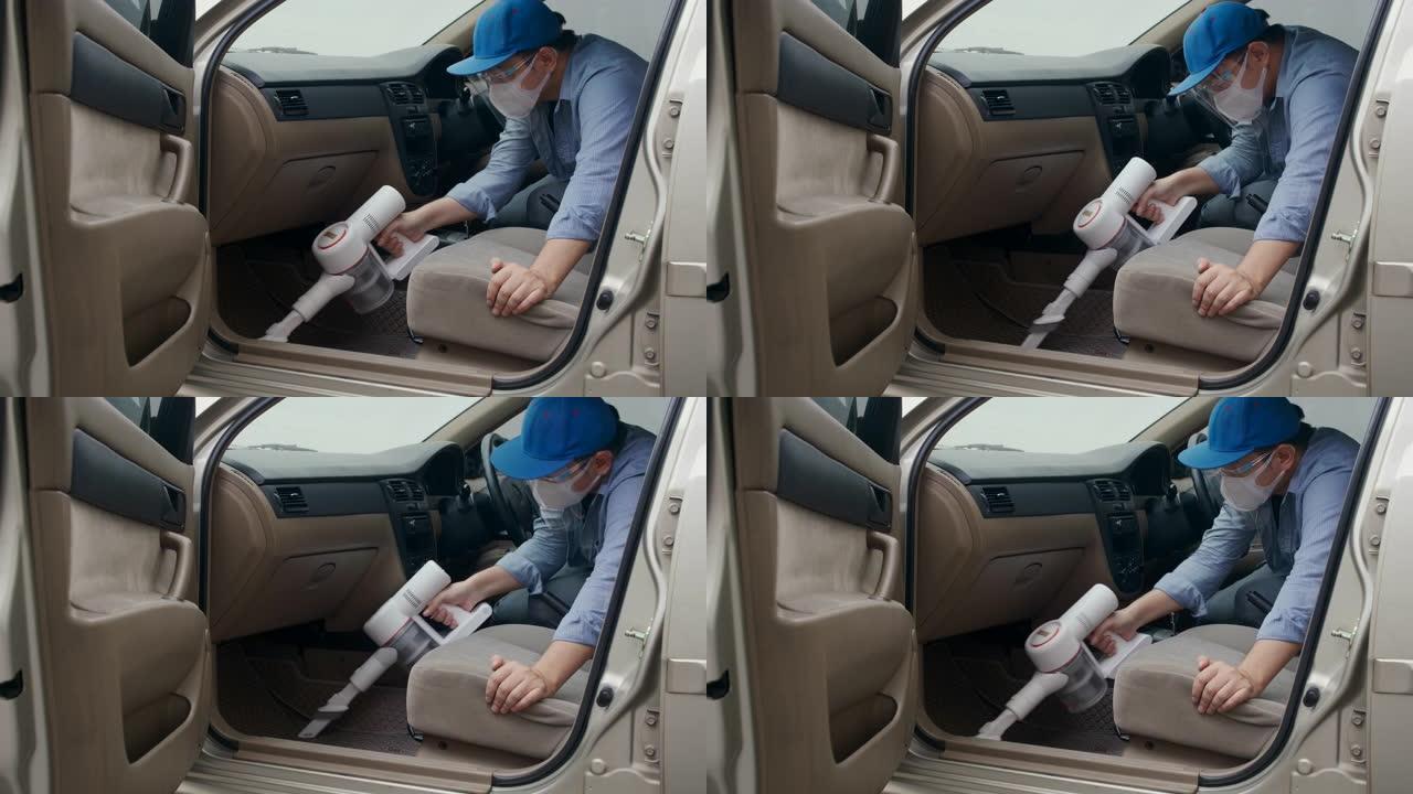 亚洲男子用吸尘器吸尘汽车以预防传染病。