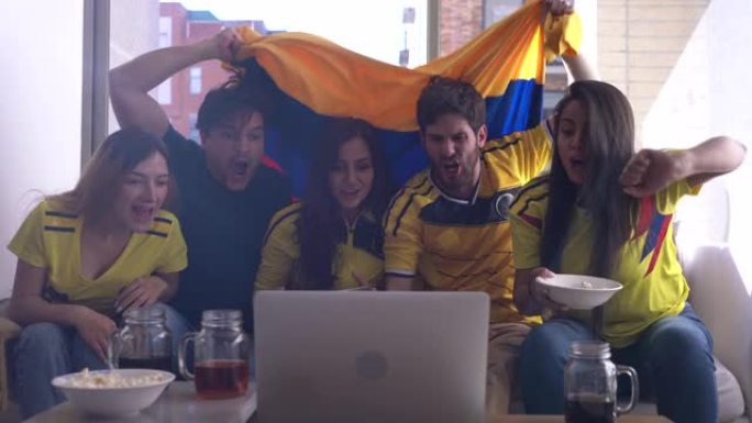 拉丁美洲一群朋友在笔记本电脑上观看足球比赛，庆祝比分非常兴奋和快乐