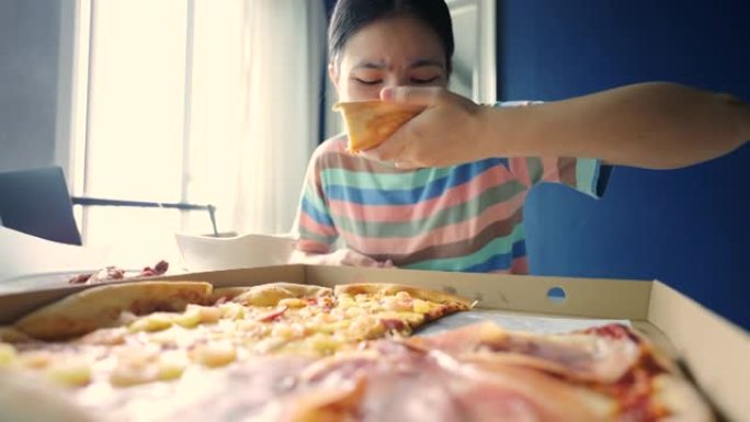 亚洲少女在家享用披萨。
