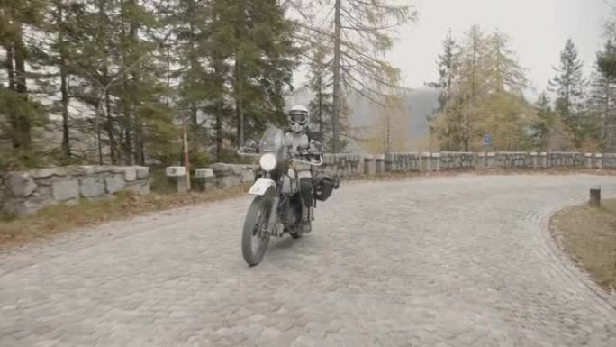 载满行李的摩托车在阴天穿越山区铺砌的道路