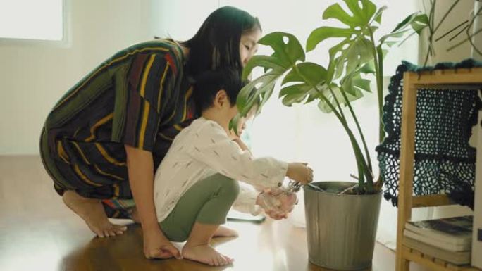 亚洲母亲和她可爱的儿子浇水植物