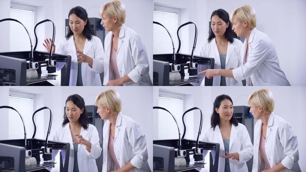 两名女性生物医学工程师谈论在3D打印机中构建的大脑模型