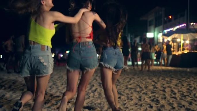 一群亚洲女人在热带岛屿海滩的满月之夜派对上一起跳舞。