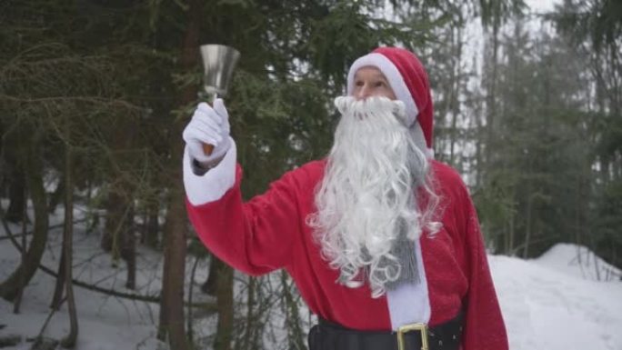 男人打扮成圣诞老人在森林里敲响钟声