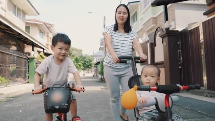 可爱的亚洲男孩和他的兄弟在户外骑自行车