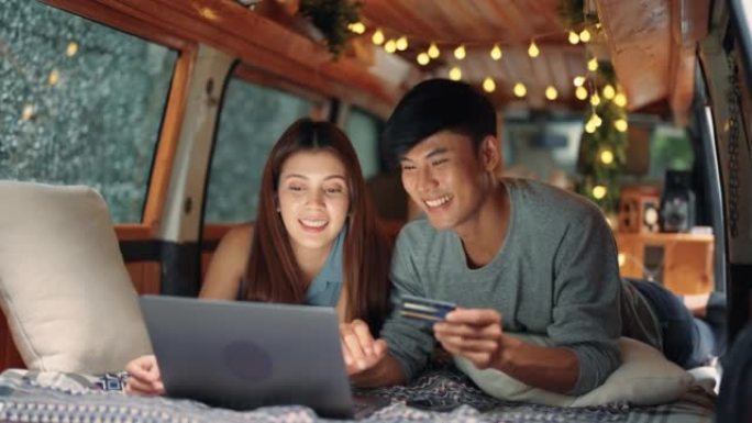快乐的年轻亚洲夫妇在汽车露营期间在线购物
