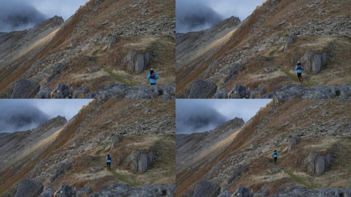 女子越野跑运动员在高山环境中跑步，雪峰在后面