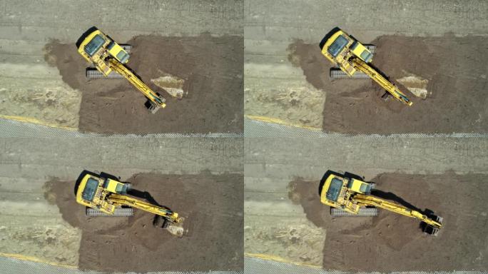 黄色挖掘机，带连续履带。鸟瞰图。找平挖掘机。施工现场准备。填充和清空挖掘机铲斗和机舱旋转。
