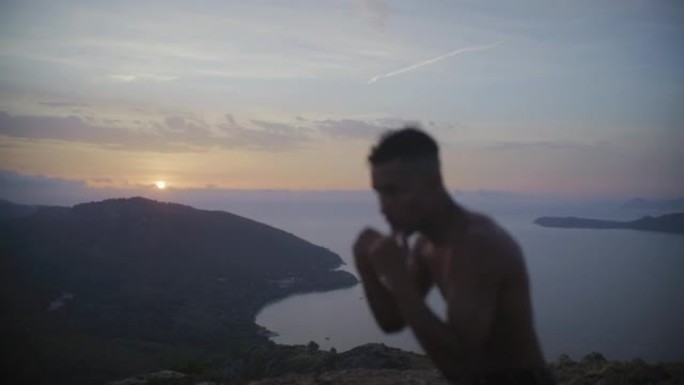 男运动员在悬崖上训练和拳打脚踢。练习拳击动作和拳打